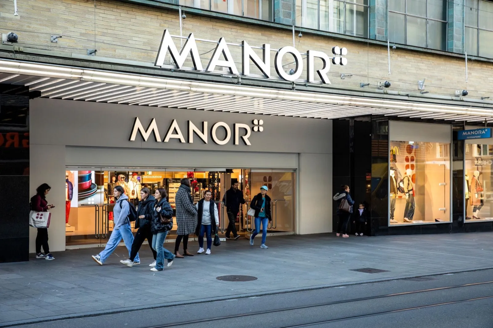 Menschen vor einem Manor-Warenhaus